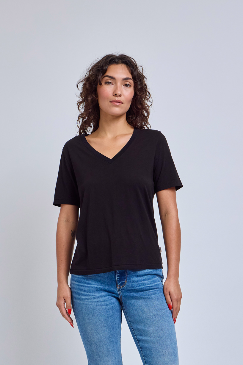 Woman wearing a black t-shirt and blue jeans against a plain background | model-size: 4