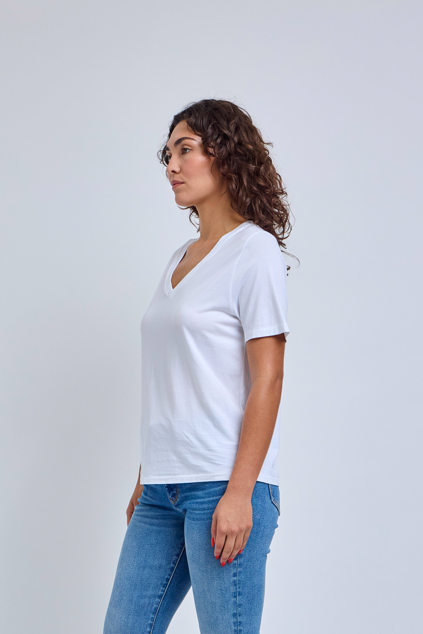 Woman wearing a plain white t-shirt and blue jeans against a light gray background