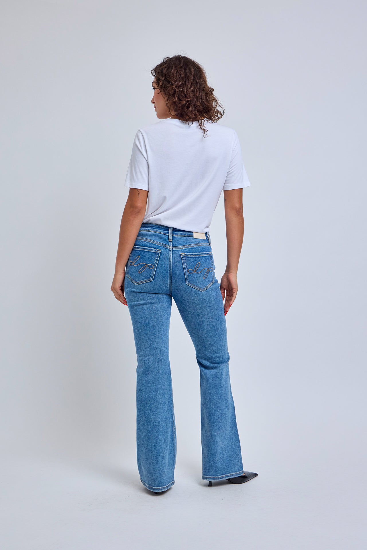 Person wearing blue jeans and a white t-shirt on a plain background