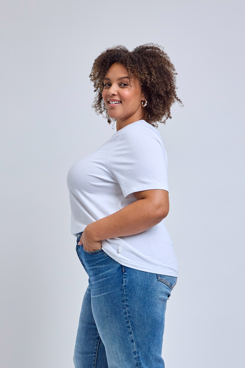Woman wearing a white t-shirt and blue jeans on a light gray background
