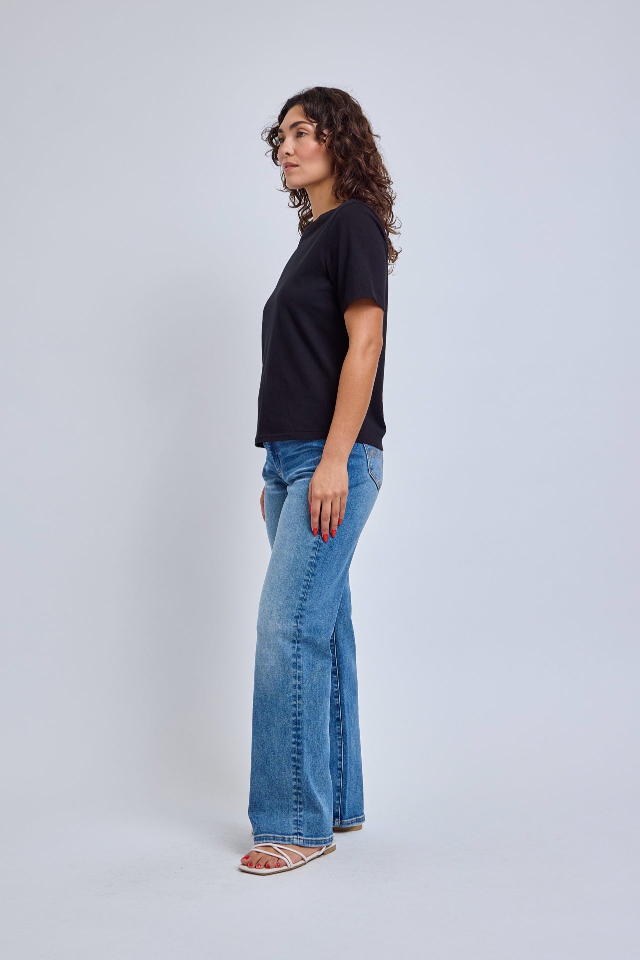 Woman wearing a black t-shirt and blue jeans on a white background