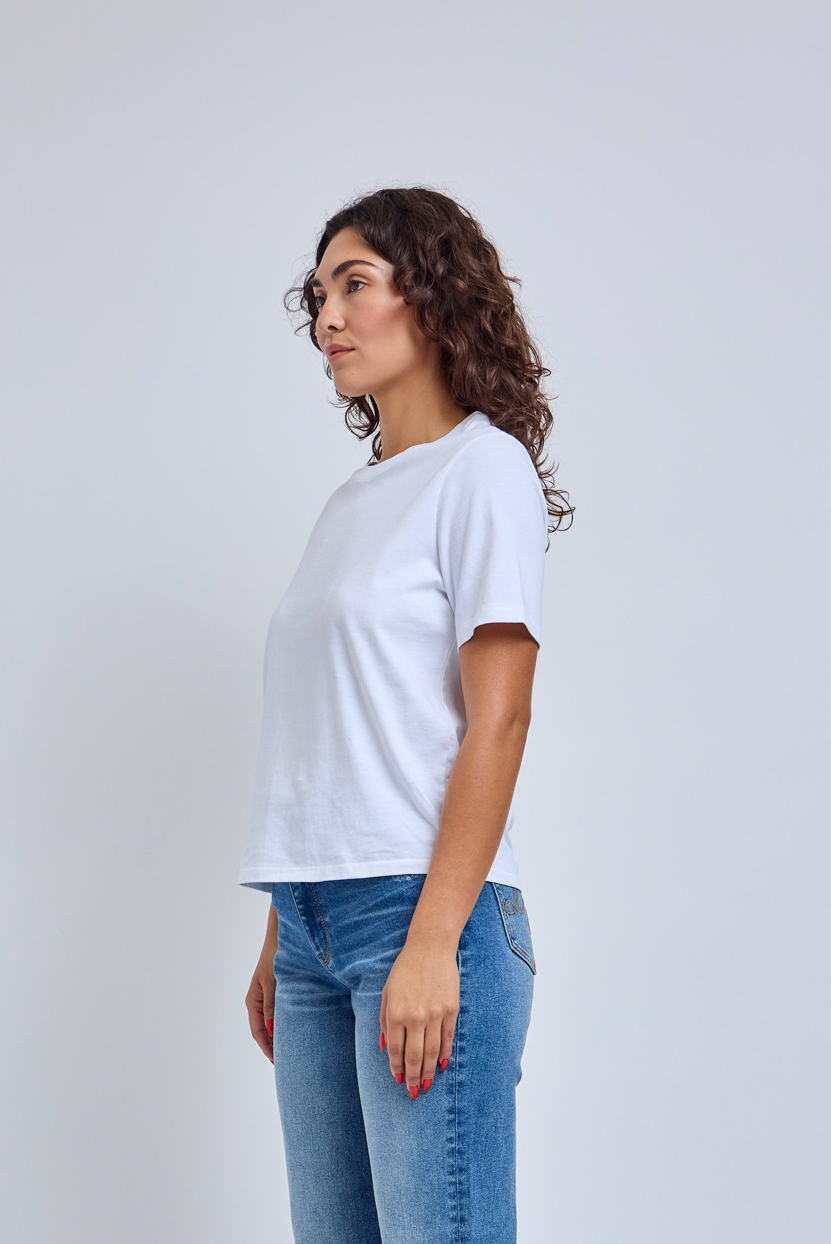 Woman wearing a plain white t-shirt and blue jeans on a light gray background