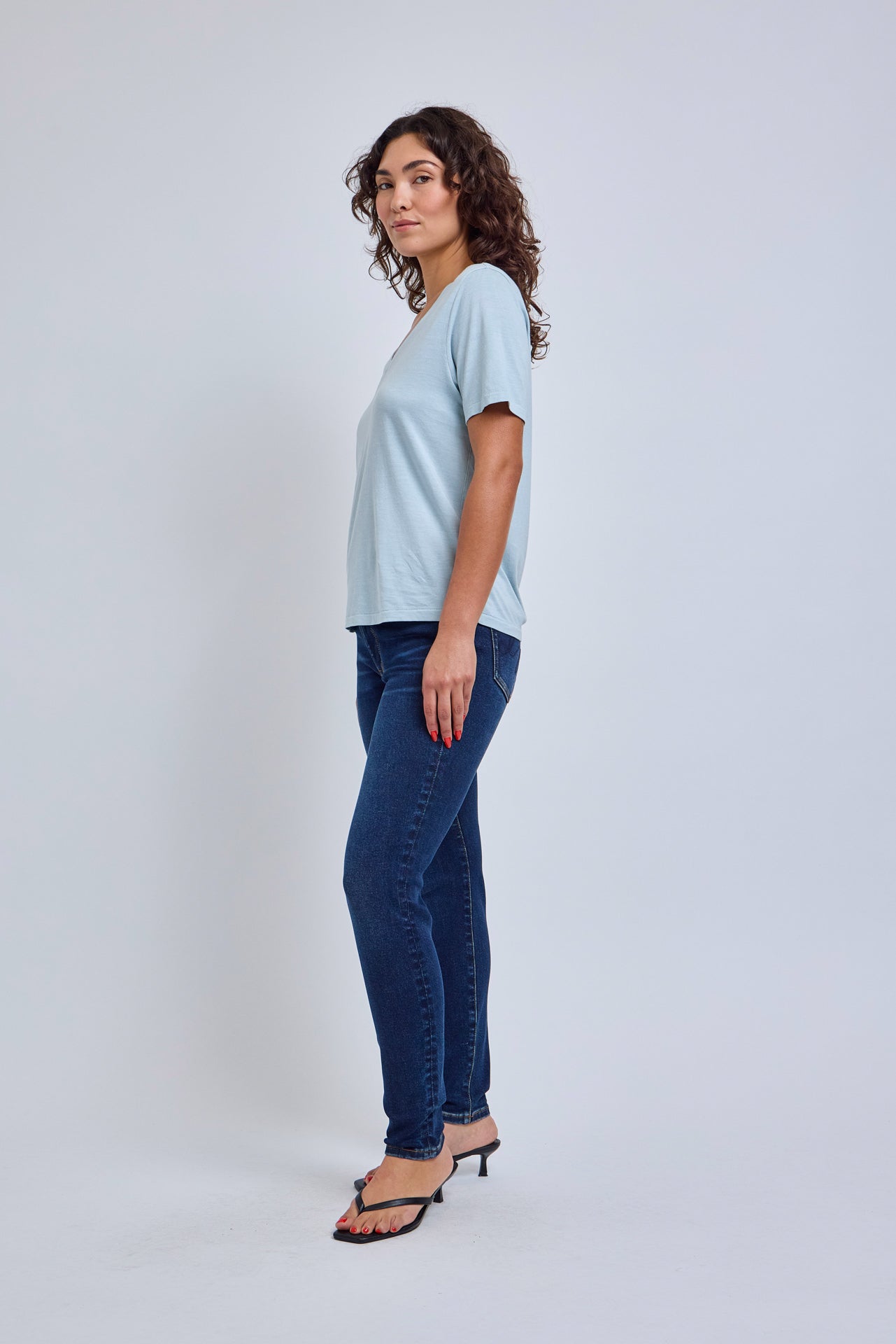 Woman wearing a light blue t-shirt and dark blue jeans on a white background