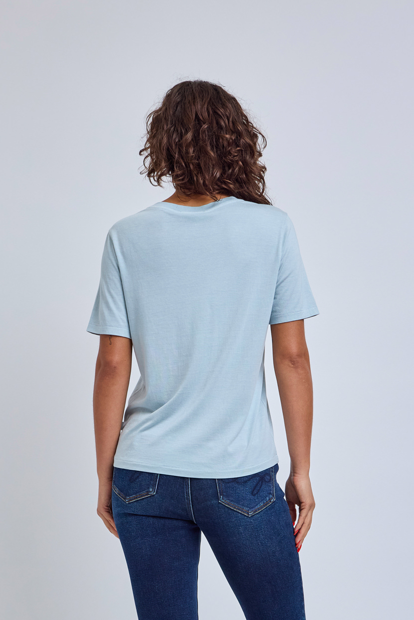 Person wearing a light blue t-shirt and blue jeans on a plain background