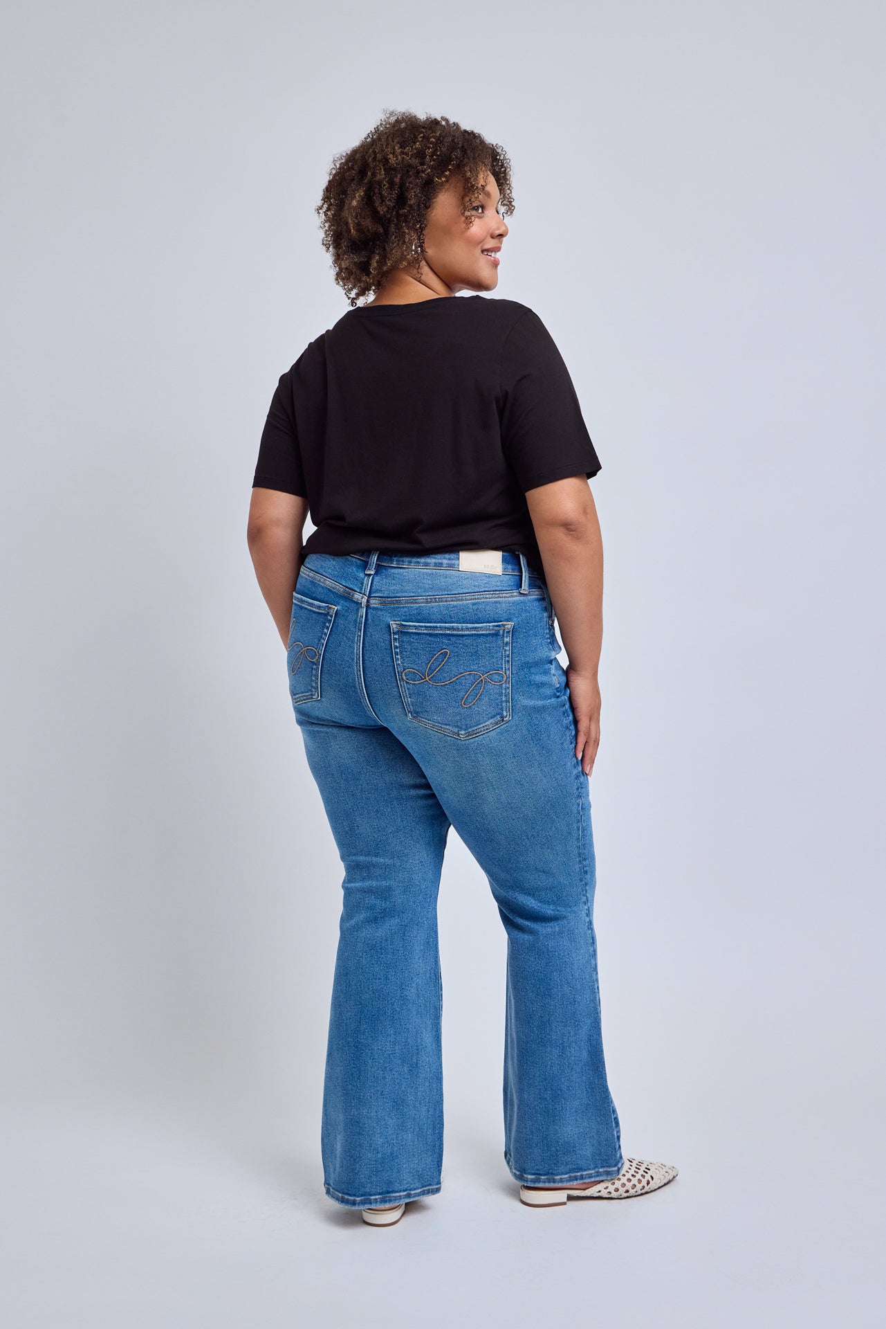 Person wearing blue jeans and a black shirt on a light gray background