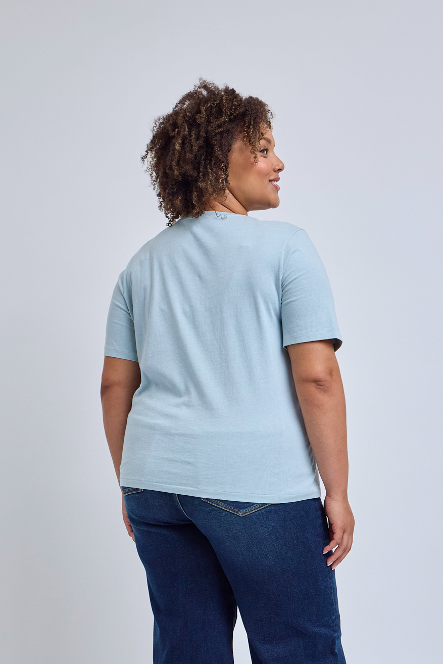 Person wearing a light blue t-shirt and dark blue jeans on a plain background