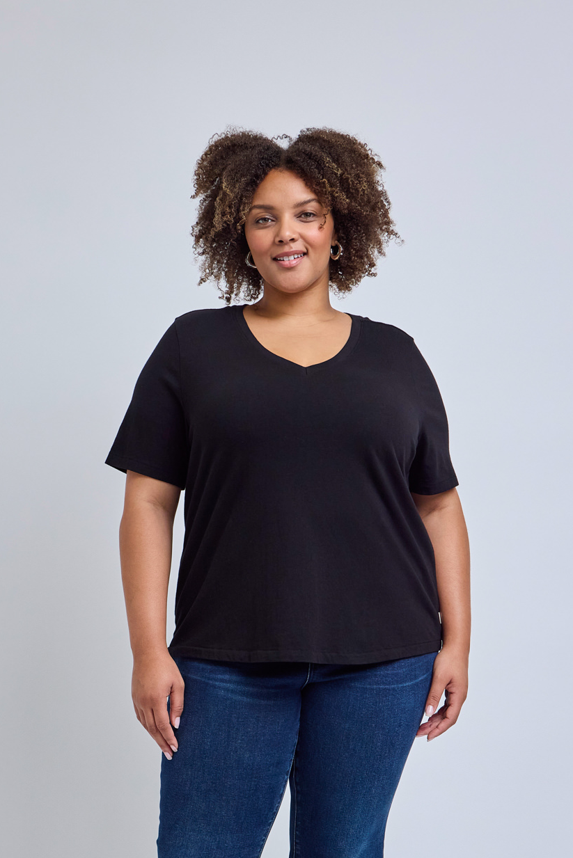 Woman wearing a black t-shirt and blue jeans against a gray background | model-size: 16