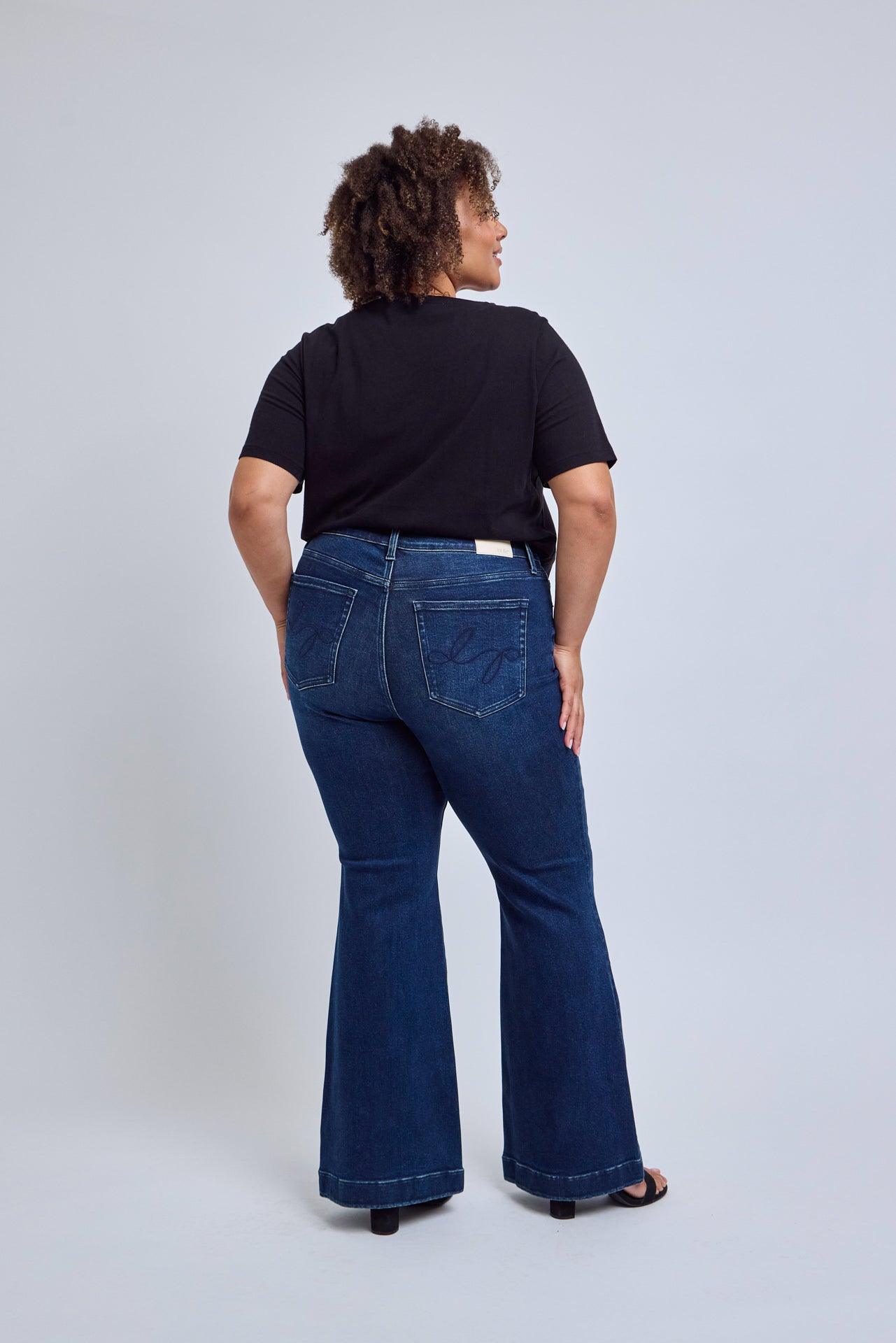 Person wearing blue jeans and a black shirt on a white background