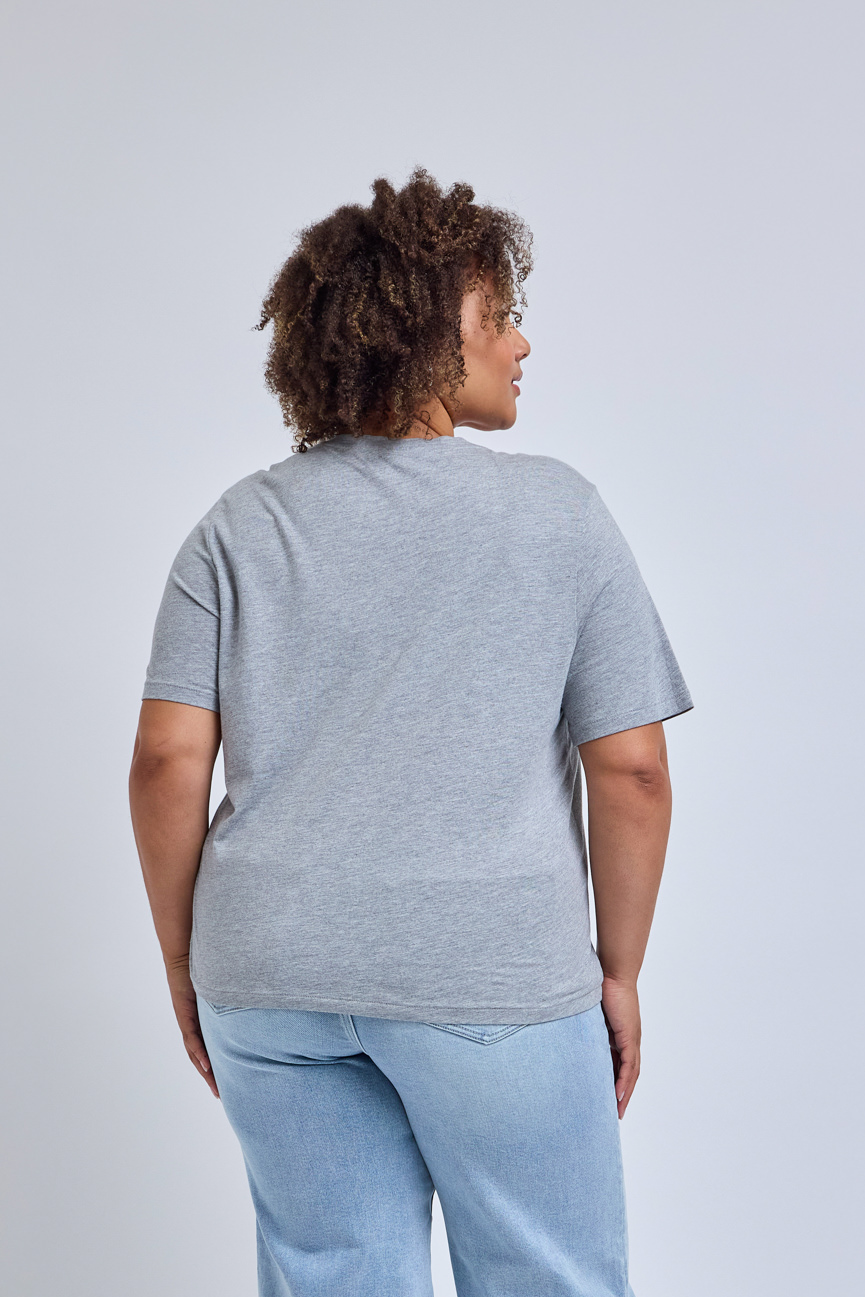 Person wearing a gray t-shirt and light blue jeans on a plain background