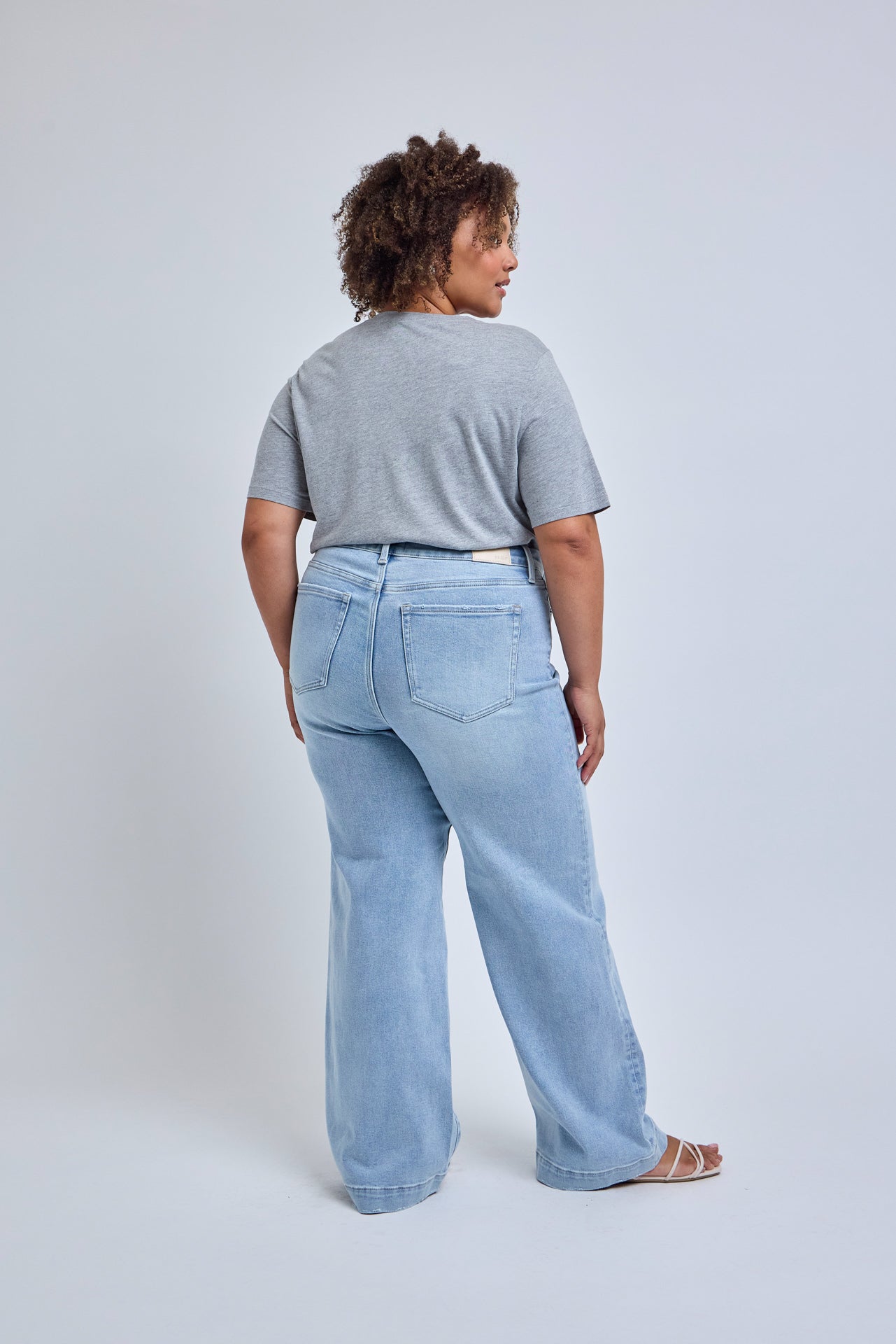 Person wearing light blue jeans and a gray shirt on a white background