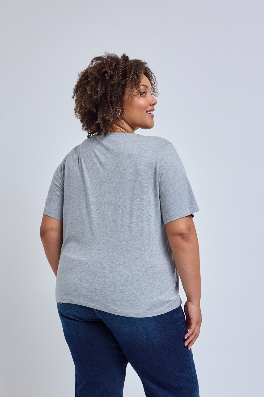 Woman wearing a gray t-shirt and blue jeans on a light gray background