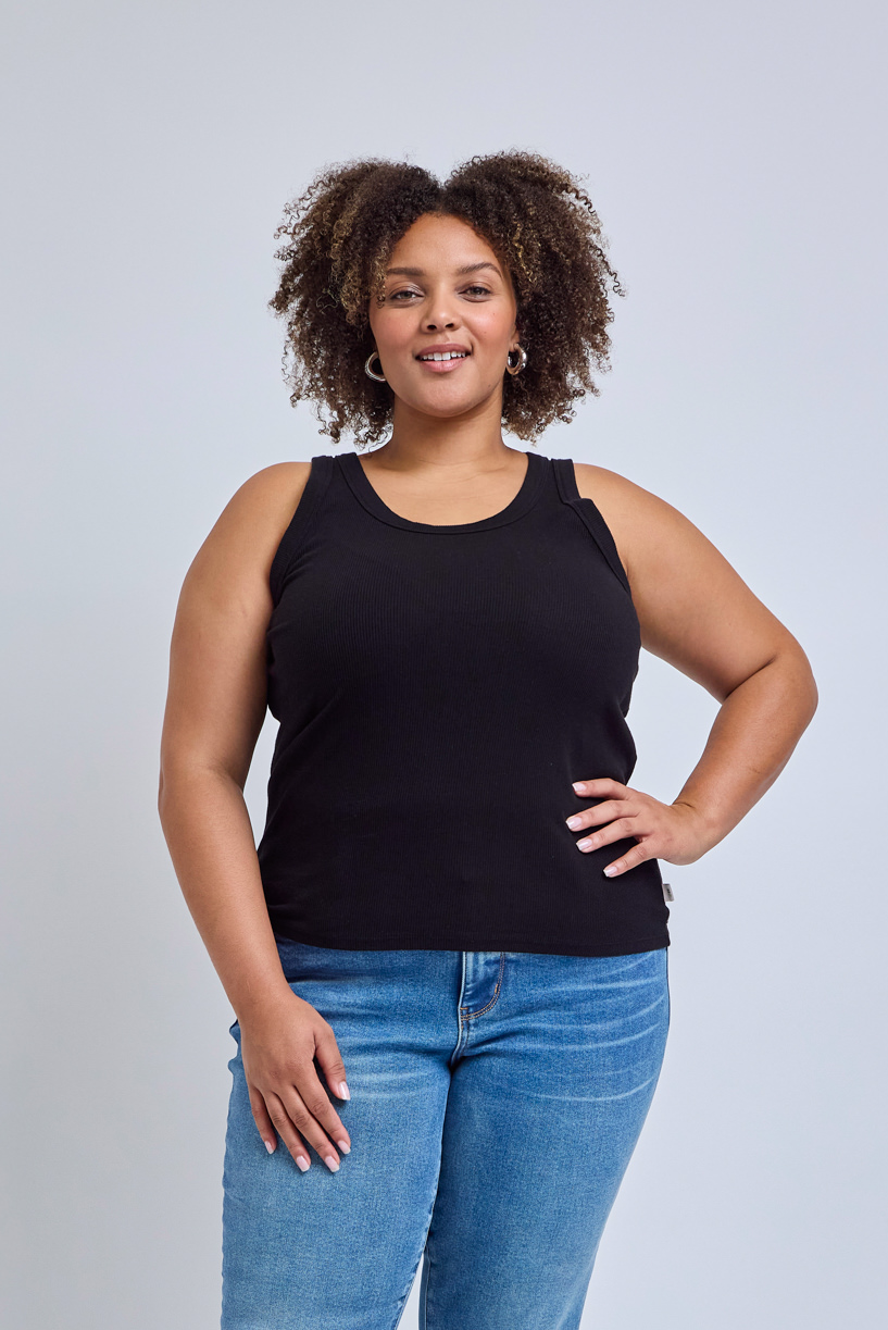 Woman wearing a black tank top and blue jeans against a gray background | model-size: 16