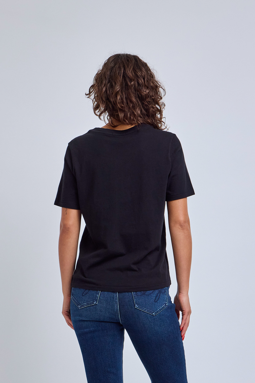 Person wearing a black t-shirt and blue jeans on a light gray background