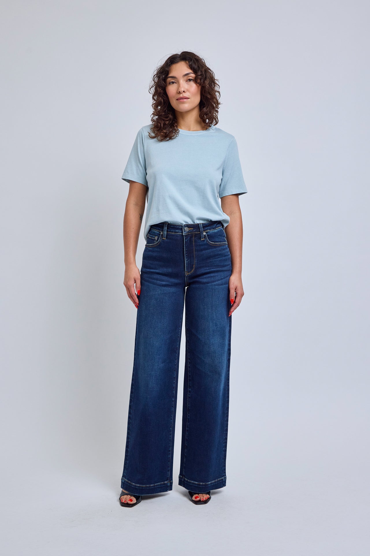 Woman wearing a light blue t-shirt and dark blue jeans on a white background