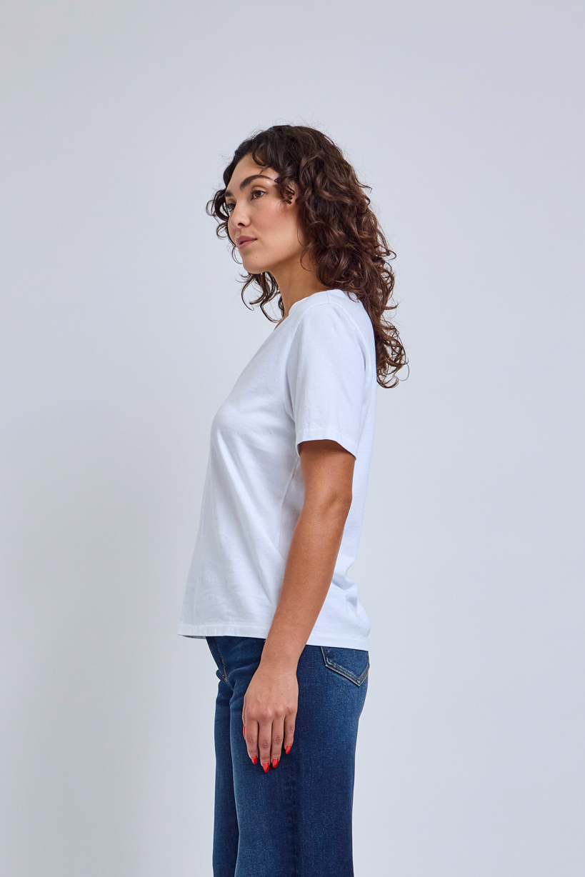 Woman wearing a plain white t-shirt and blue jeans on a light gray background