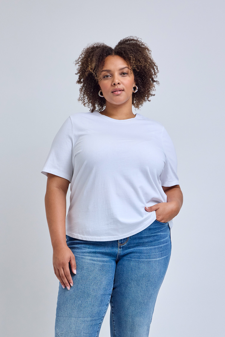 Person wearing a plain white t-shirt and blue jeans on a light gray background | model-size: 16