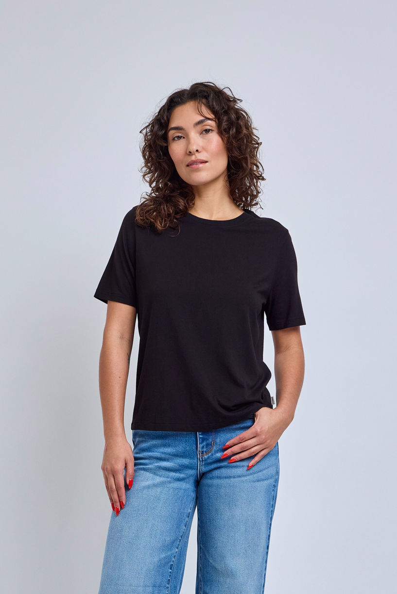 Woman wearing a black t-shirt and blue jeans against a light gray background | model-size: 4