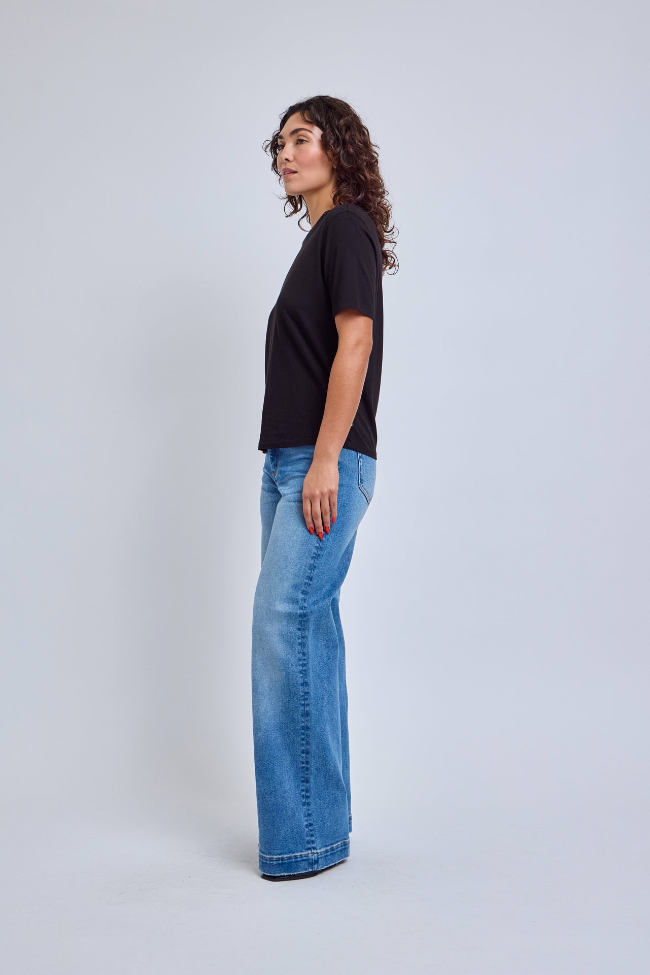 Woman wearing a black t-shirt and blue jeans on a white background