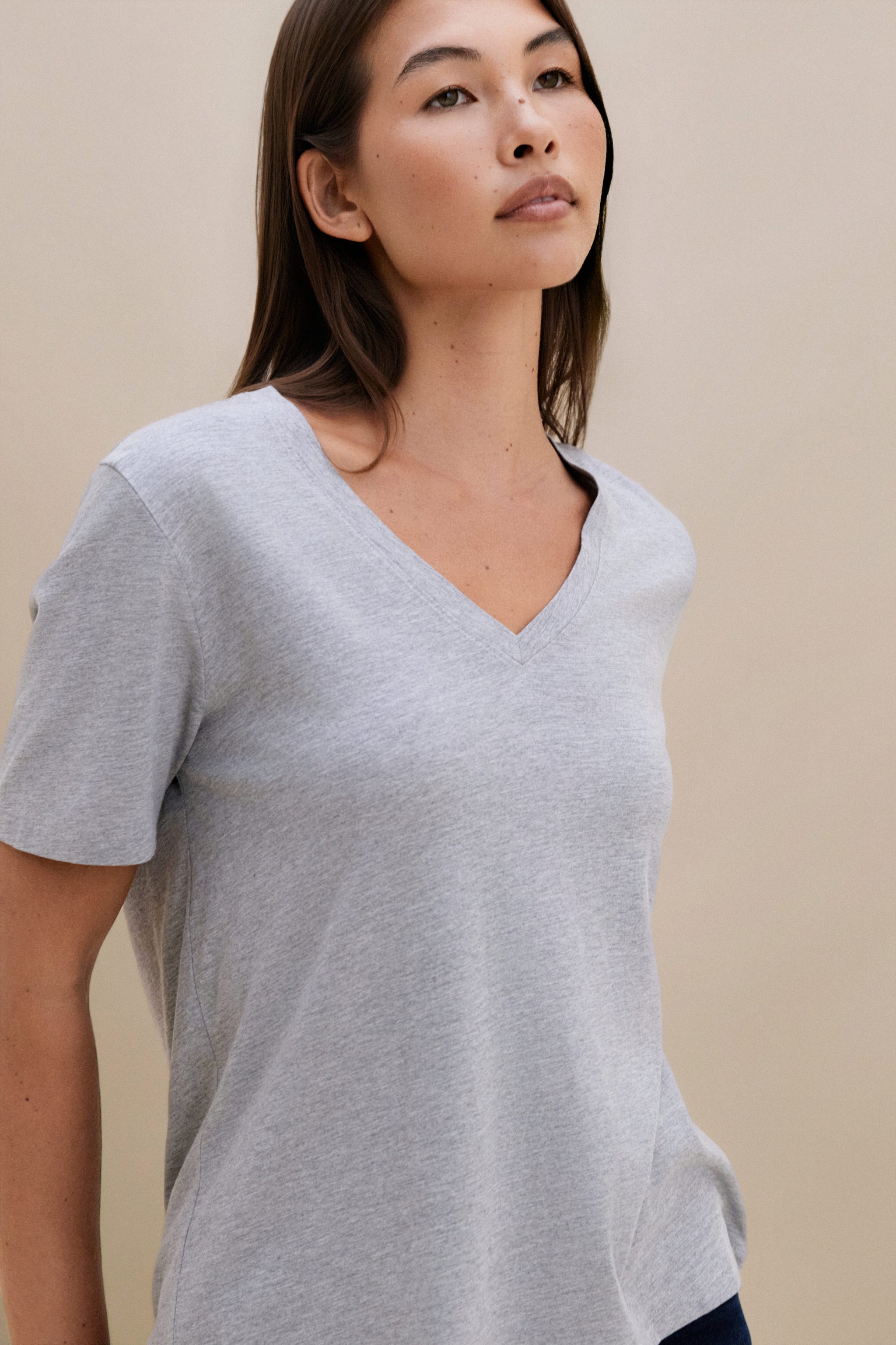 Woman wearing a gray t-shirt against a beige background