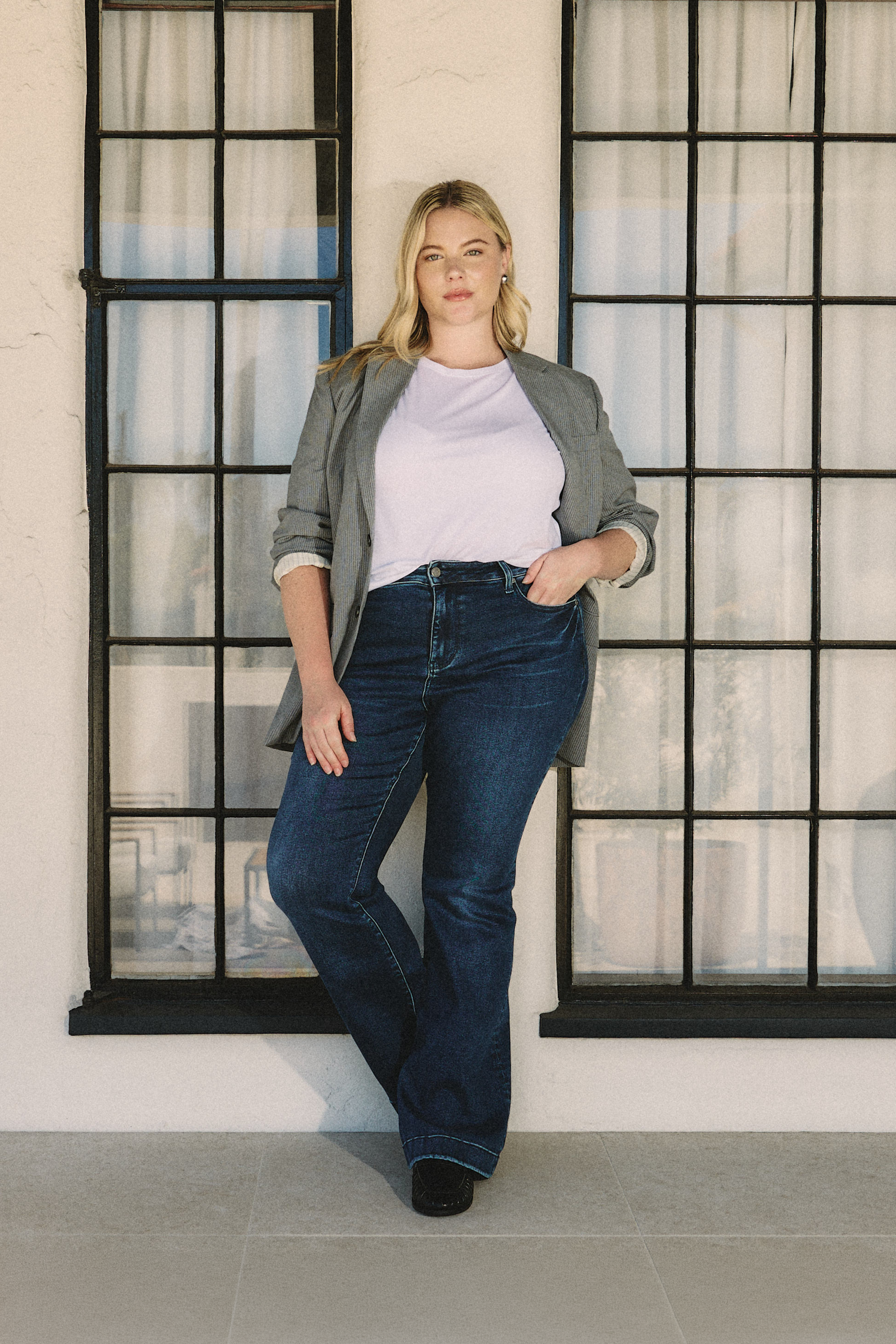 Woman standing in front of a window with a neutral background