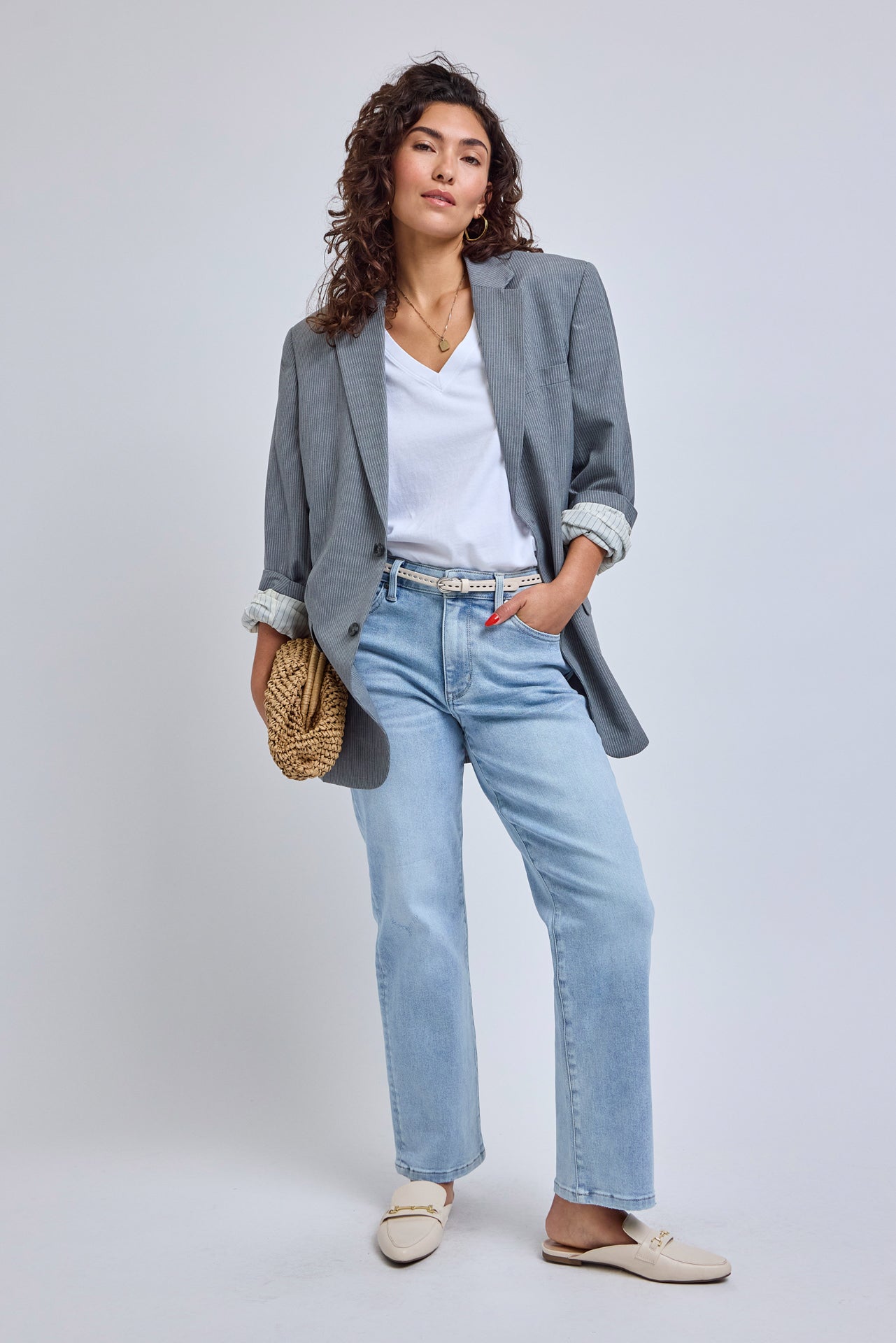 Woman wearing a gray blazer, white shirt, light blue jeans, and beige shoes on a white background | model-size: 4
