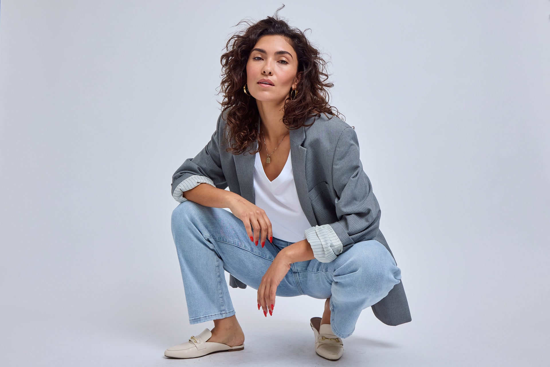 Woman wearing a gray jacket and light blue jeans on a white background