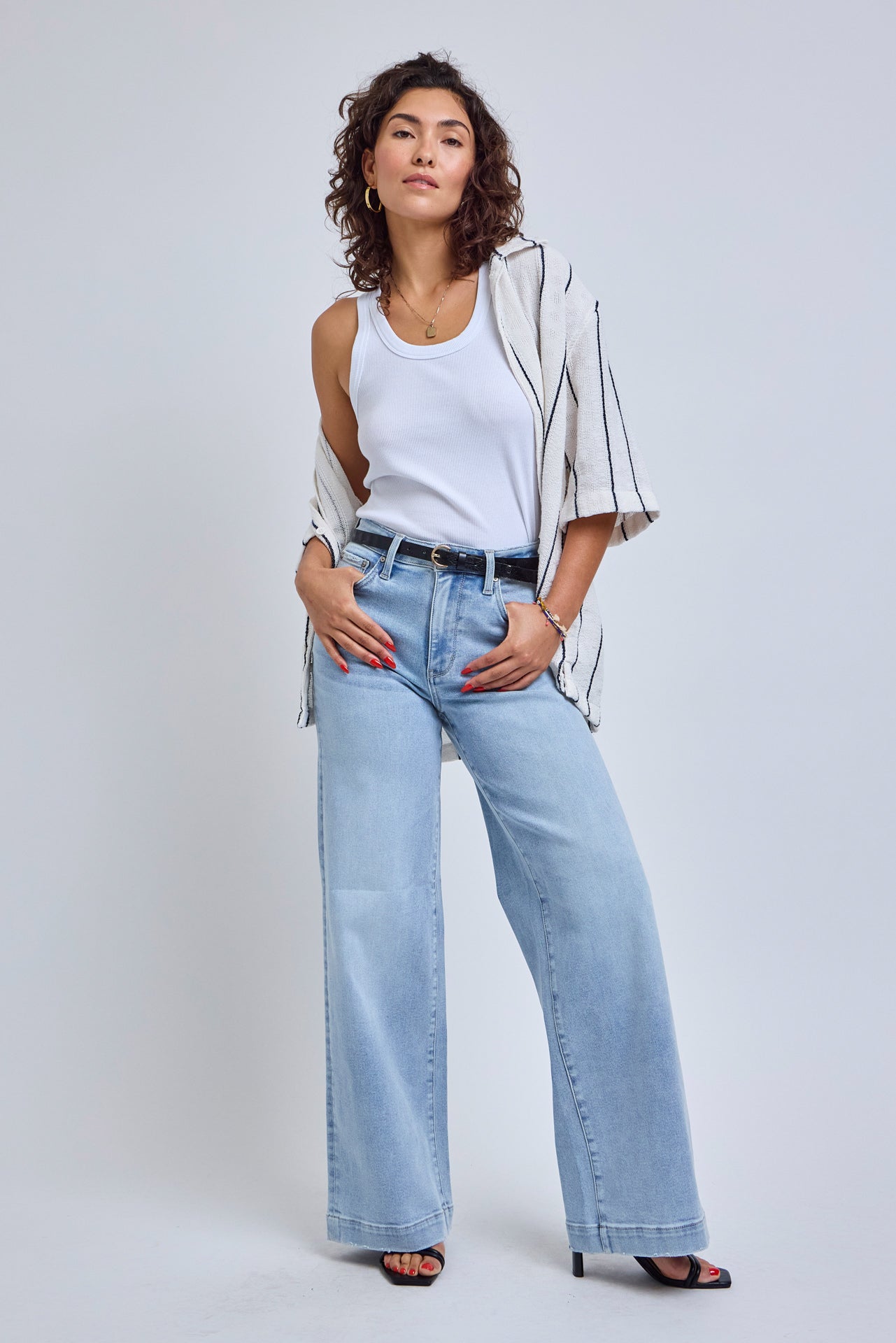 Woman wearing a white top, beige jacket, and light blue jeans on a white background | model-size: 4