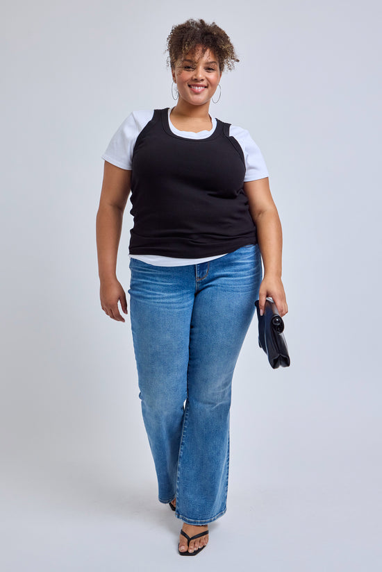 woman wearing a white t-shirt with a black tank top styled over it and blue jeans