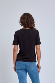 Person wearing a black t-shirt and blue jeans on a light gray background