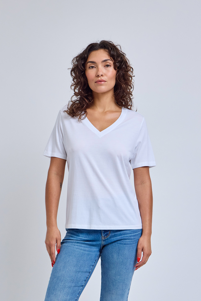 Woman wearing a plain white t-shirt and blue jeans against a light gray background | model-size: 4