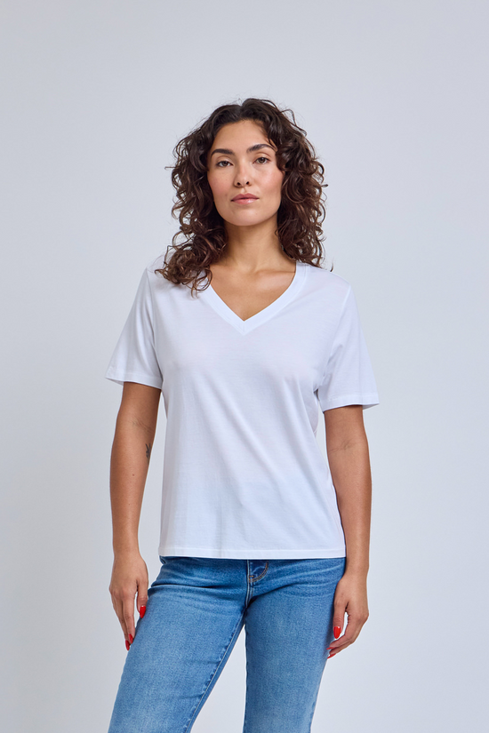 Woman wearing a plain white t-shirt and blue jeans against a light gray background | model-size: 4