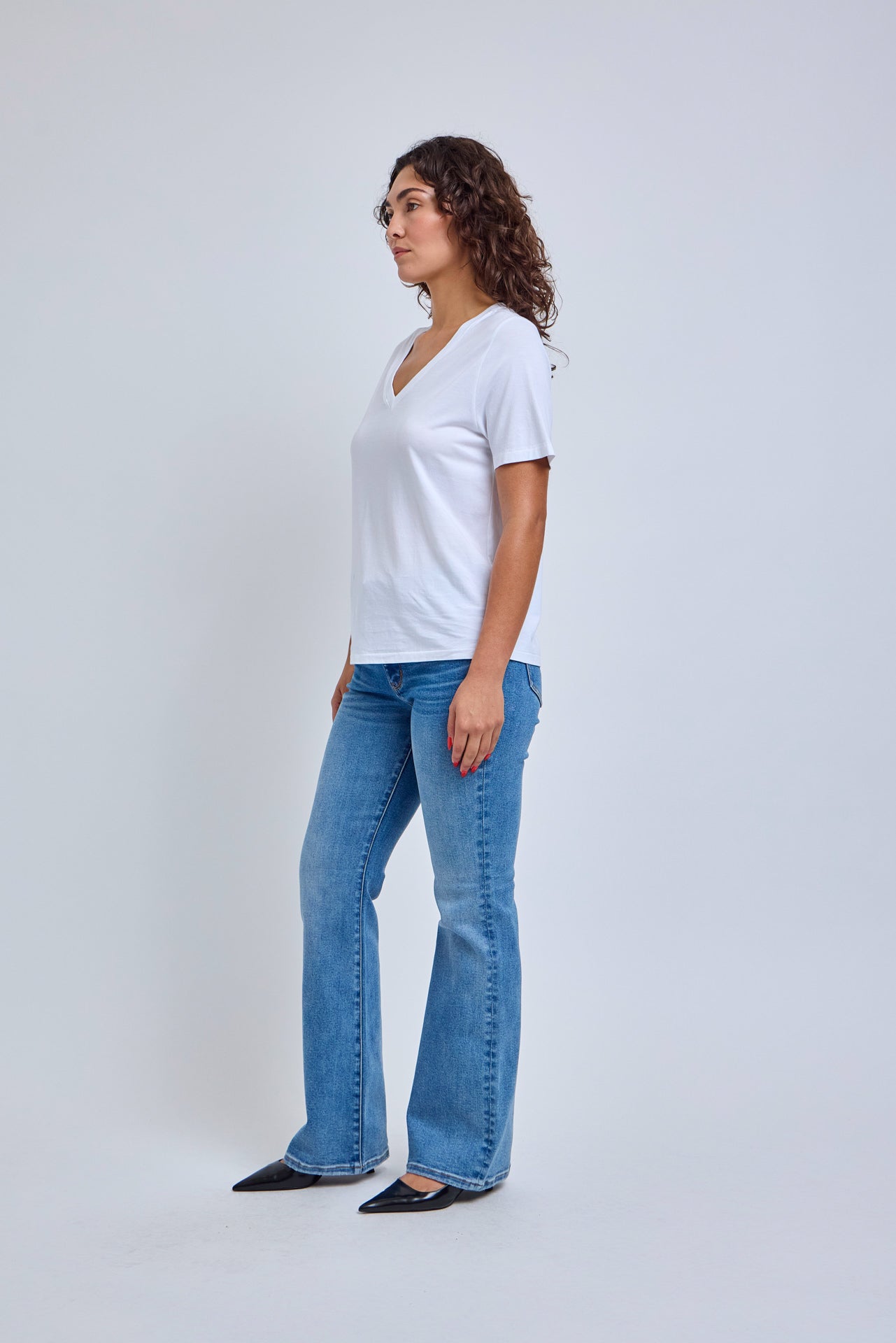 Woman wearing a white t-shirt and blue jeans on a white background