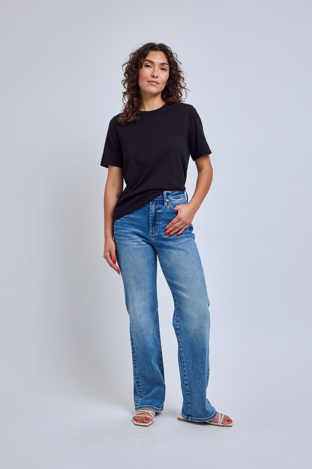 Woman wearing a black t-shirt and blue jeans on a white background 