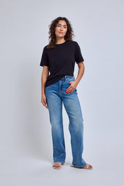 Woman wearing a black t-shirt and blue jeans on a white background 