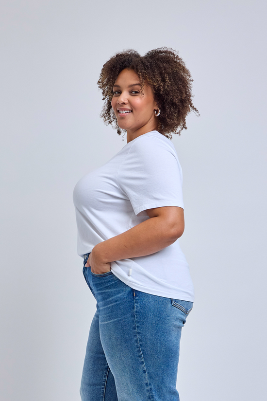 Woman wearing a white t-shirt and blue jeans on a light gray background