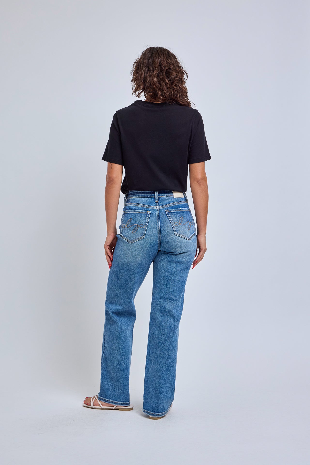 Person wearing blue jeans and a black shirt on a white background
