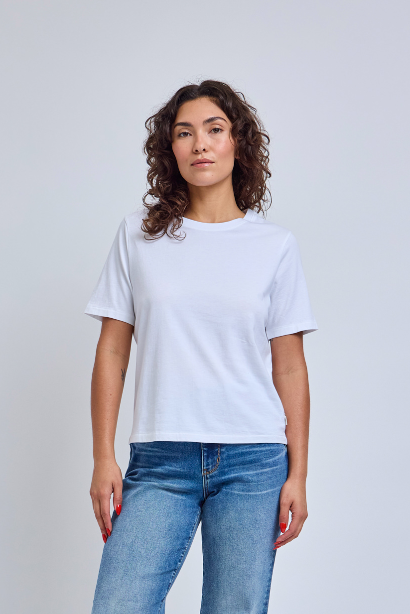 Woman wearing a plain white t-shirt and blue jeans against a light gray background | model-size: 4