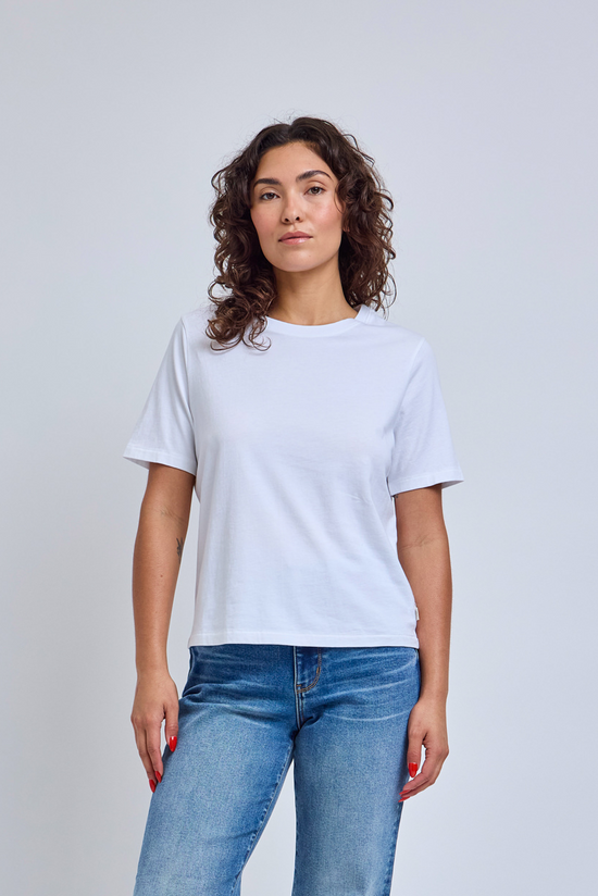 Woman wearing a plain white t-shirt and blue jeans against a light gray background | model-size: 4