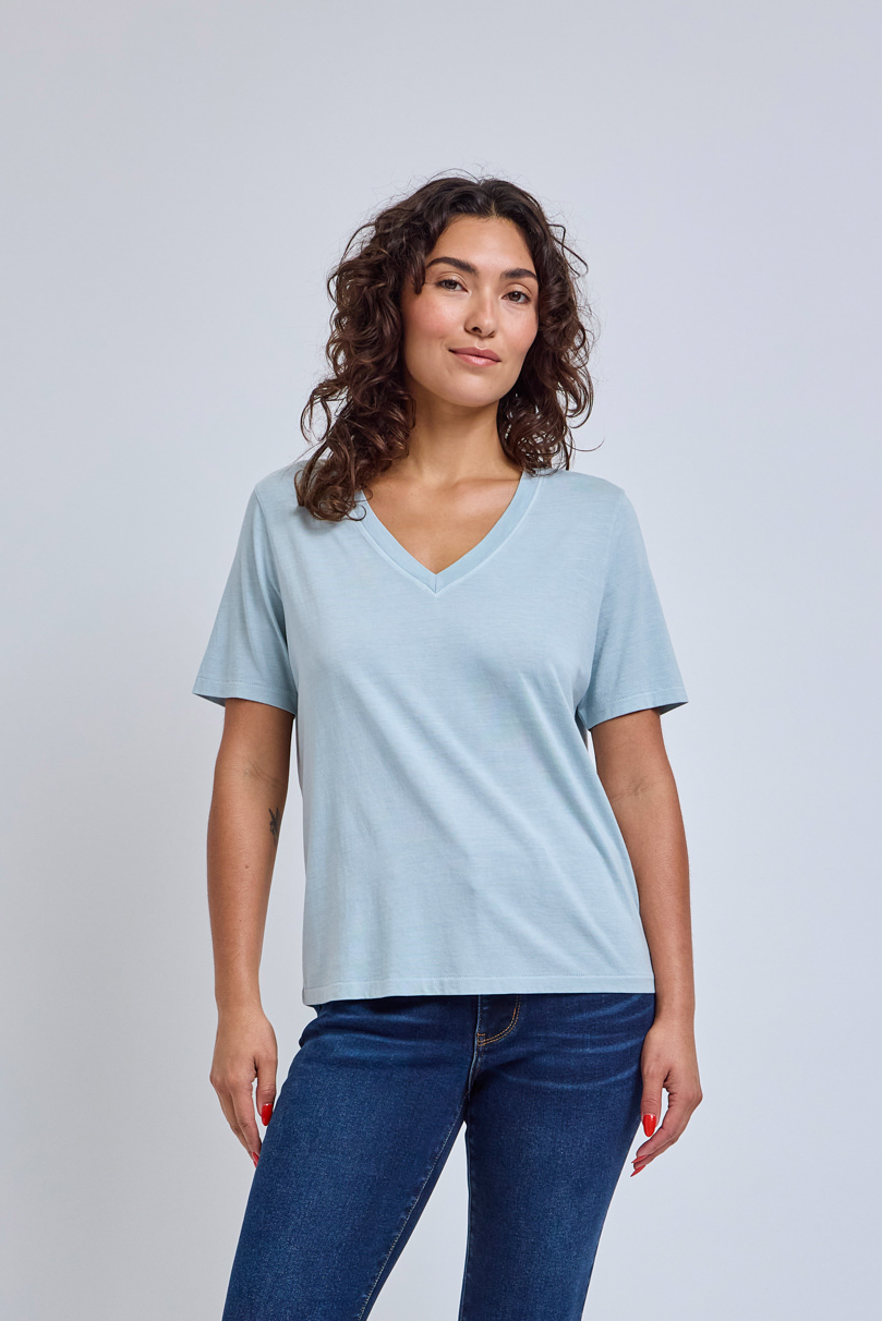 Woman wearing a light blue t-shirt and blue straight jeans against a light gray background | model-size: 4