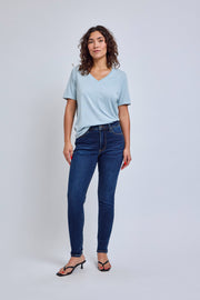 Woman wearing a light blue t-shirt and dark blue jeans on a white background | model-size: 4