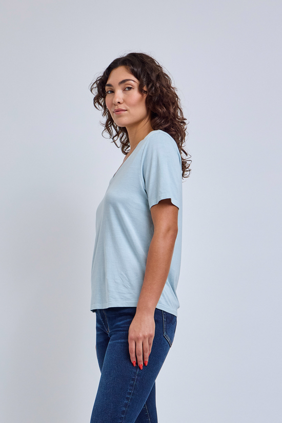 Woman wearing a light blue t-shirt and blue jeans against a white background