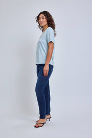 Woman wearing a light blue t-shirt and dark blue jeans on a white background