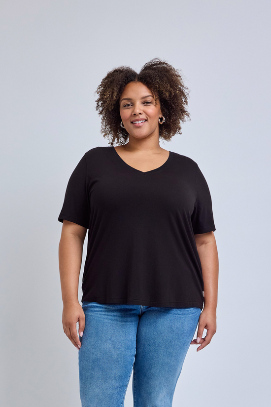 Woman wearing a black t-shirt and blue jeans against a gray background | model-size: 16