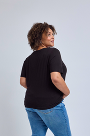 Person wearing a black t-shirt and blue jeans on a light gray background