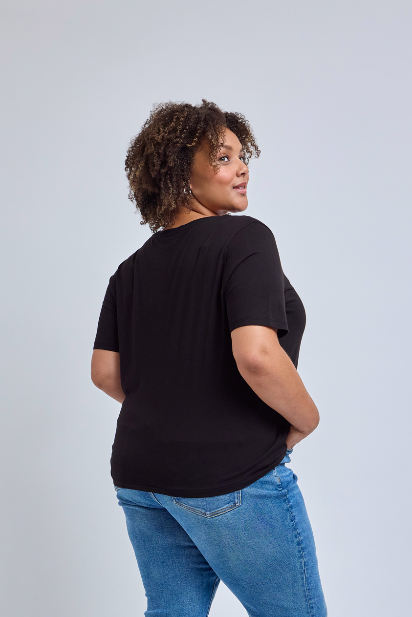 Person wearing a black t-shirt and blue jeans on a light gray background