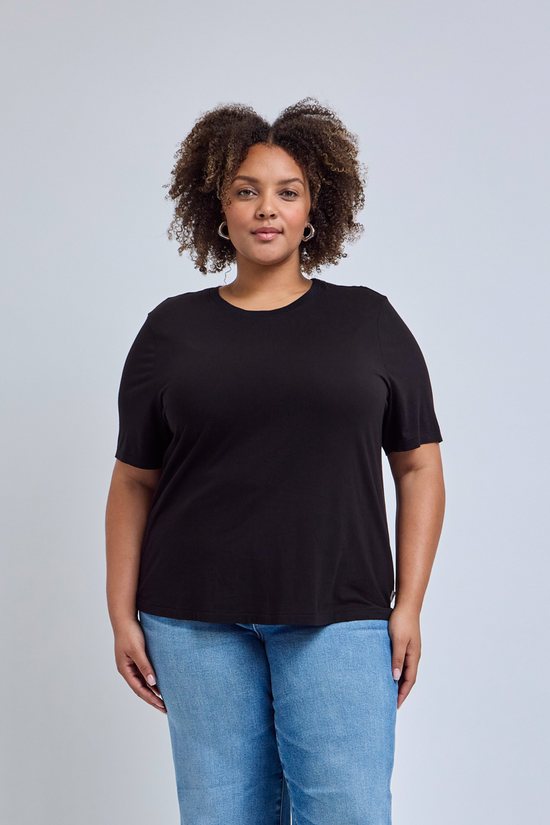 Person wearing a black t-shirt and blue jeans against a gray background | model-size: 16