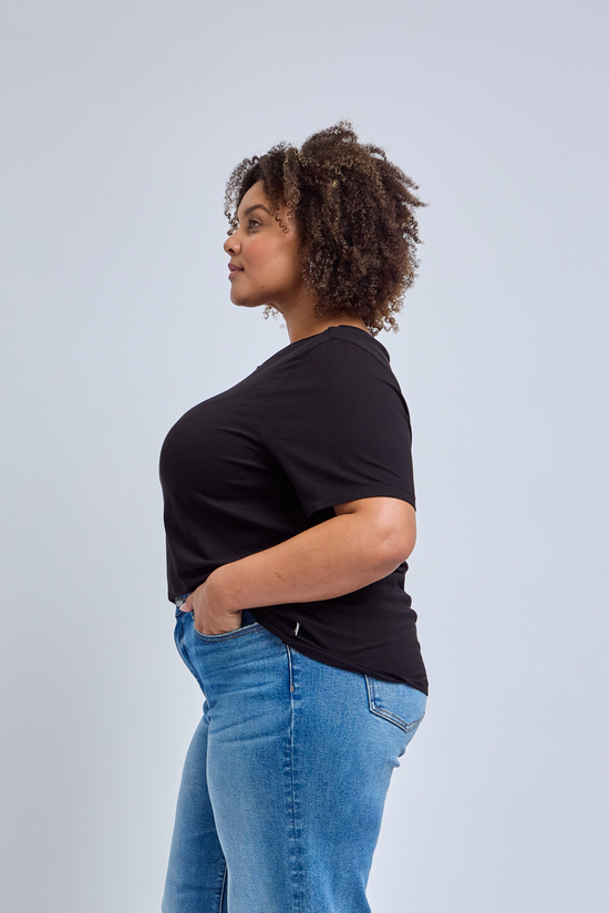 Person wearing a black t-shirt and blue jeans against a light gray background