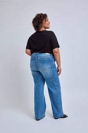 Person wearing blue jeans and a black top on a light gray background