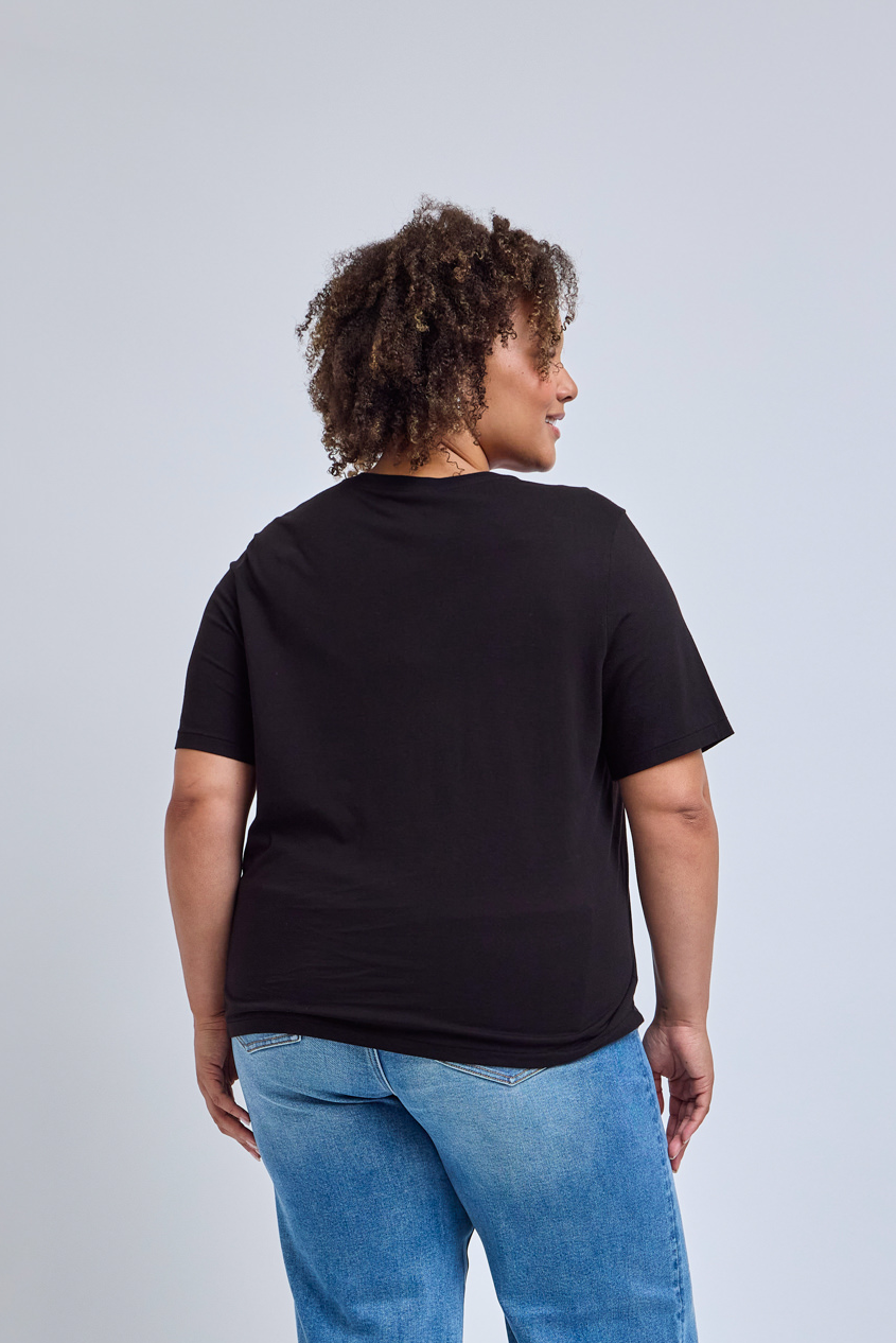 Person wearing a black t-shirt and blue jeans on a light gray background