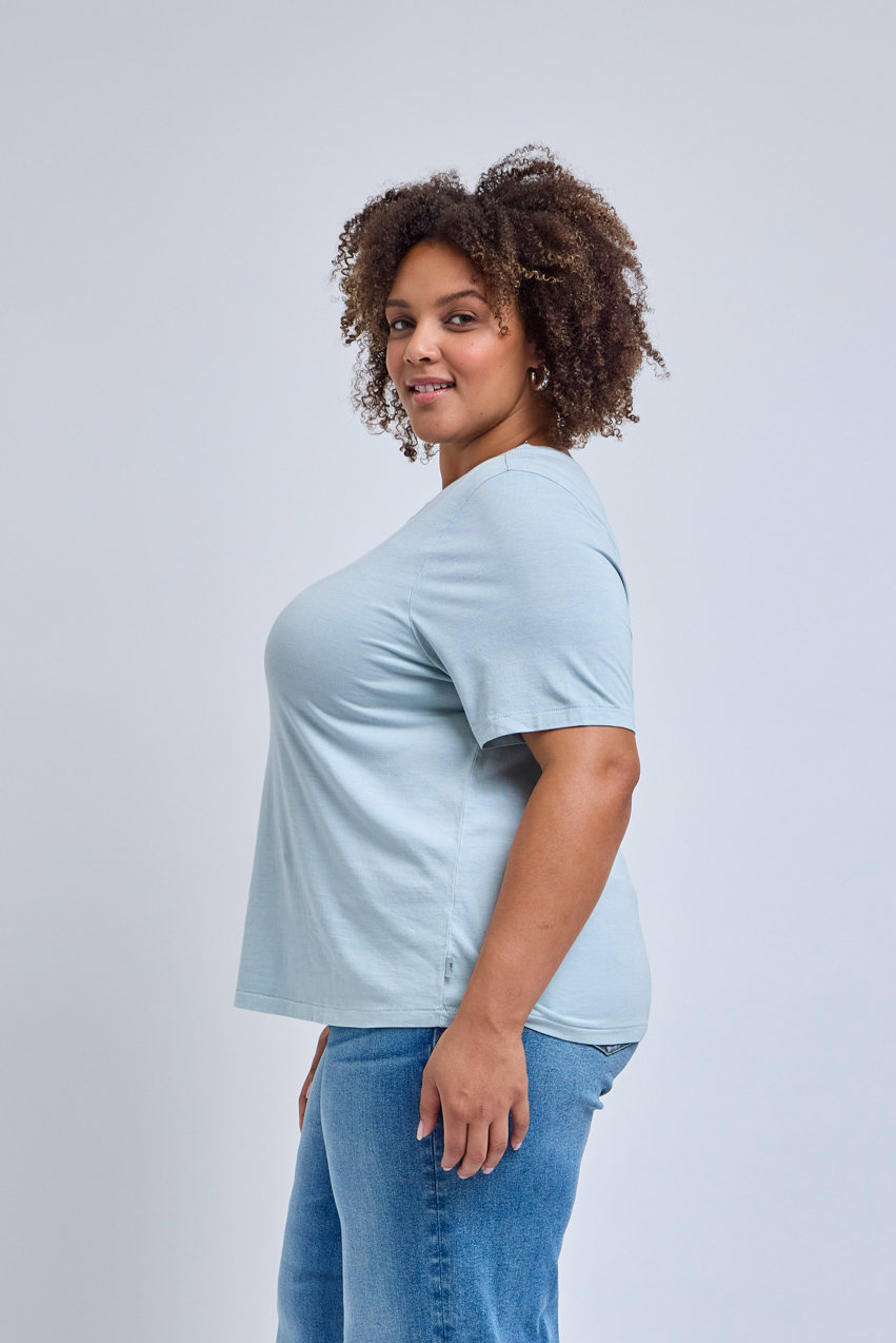 Woman wearing a light blue t-shirt and jeans on a plain background